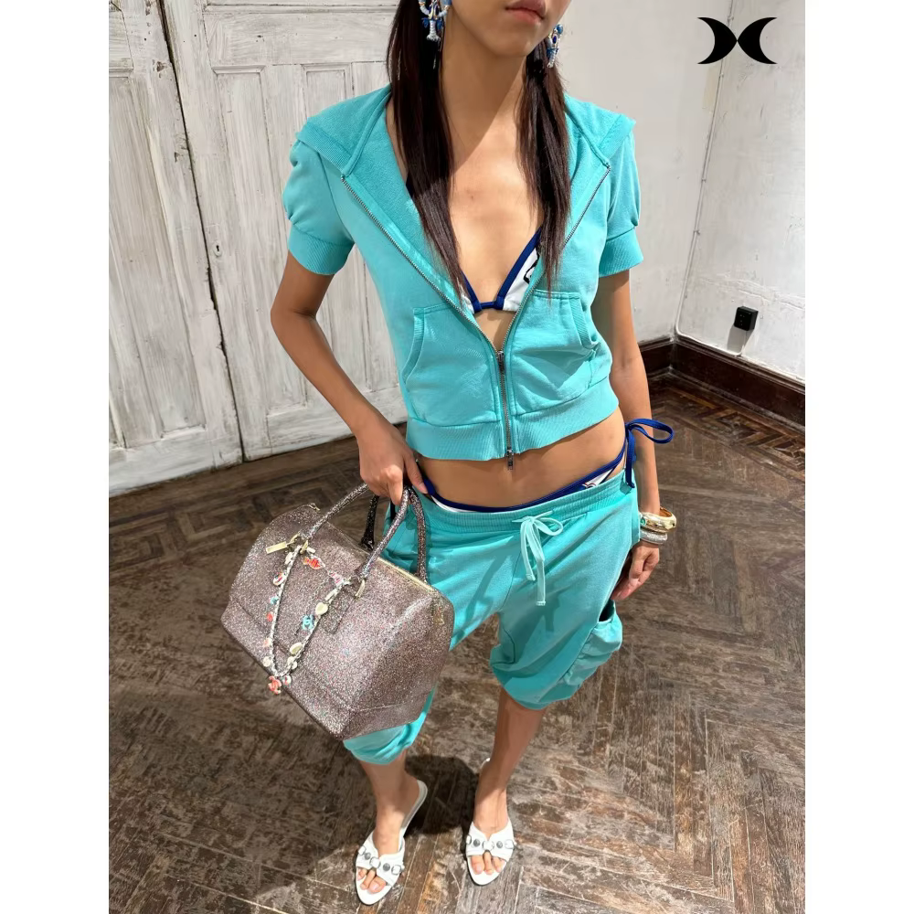 Ensemble de survêtement style streetwear américain pour femme : veste à capuche zippée à manches courtes et pantalon à sept poignées, couleur unie, style sport tendance.
