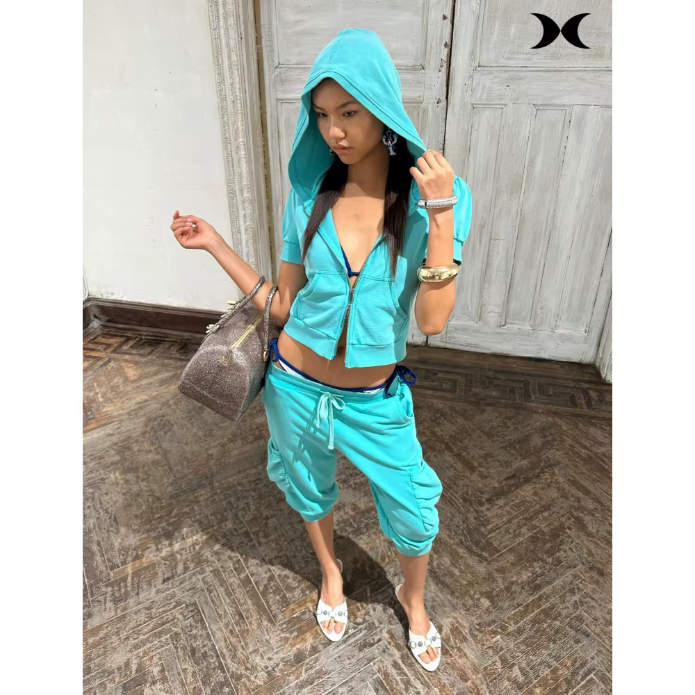 Ensemble de survêtement style streetwear américain pour femme : veste à capuche zippée à manches courtes et pantalon à sept poignées, couleur unie, style sport tendance.